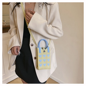 Détail du mini sac à portable en tricot jaune avec cœurs bleus et bandoulière élégante