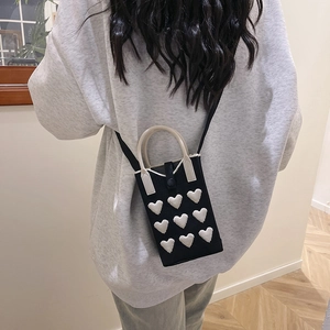 Mini sac à téléphone en tricot avec cœurs 3D blancs, porté en bandoulière par un modèle