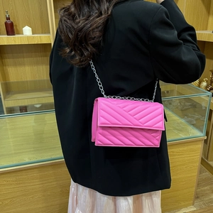 Sac bandoulière rose matelassé avec texture en V et bandoulière chaîne argentée