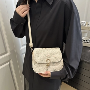 Handmade straw saddle bag with floral embroidery and gold buckle on a model