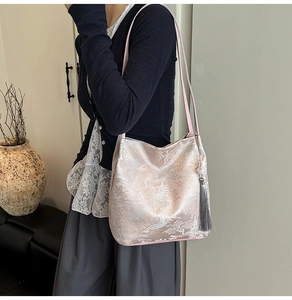 Detail view of pink silk tote bag with landscape embroidery and grey tassel pendant