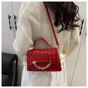 Détail du sac rouge motif crocodile avec chaîne dorée et sangle porté par un mannequin