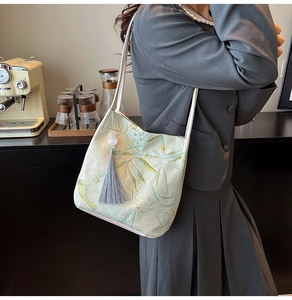 Detail of green tote bag featuring traditional bamboo embroidery and gray silk tassel