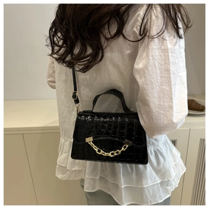 Détail du sac noir à motif crocodile avec une chaîne dorée décorative élégante
