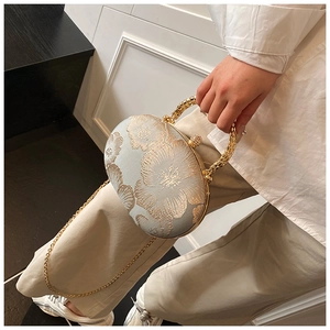 Detail of light blue clutch with gold floral embroidery and elegant metal handle
