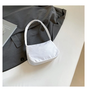 Detailed view of white nylon crescent shoulder bag on a stylish grey blazer suit jacket