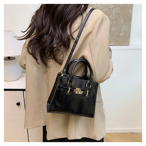 Detail of the high-shine black leather handbag with gold twist lock and elegant top handle