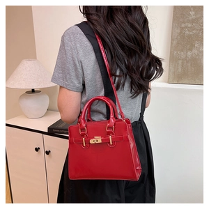Close-up of red patent leather handbag with gold metal clasp and luxury texture