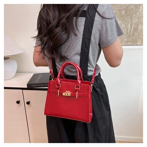 Detail of red patent leather tote bag with gold twist lock and glossy finish