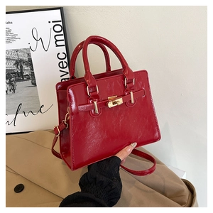 Close-up of shiny red patent leather handbag with gold metal clasp and buckle detail