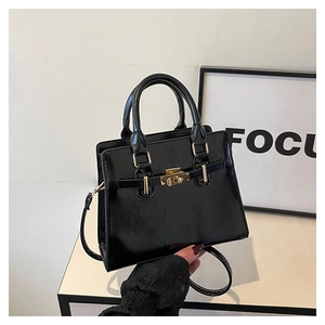 Detail view of the black patent leather handbag with golden hardware and twist-lock closure