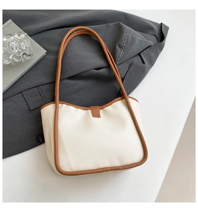 Detail of minimalist white tote bag with brown leather straps in a professional workplace setting