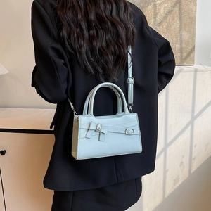 Stylish light blue crossbody handbag with a decorative bow and detachable shoulder strap
