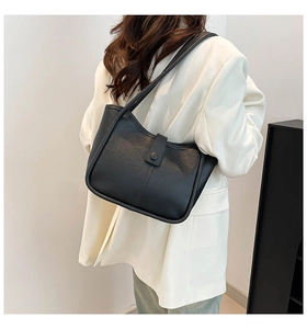 Detail of black pebbled leather tote bag with vertical stitching and slim shoulder straps