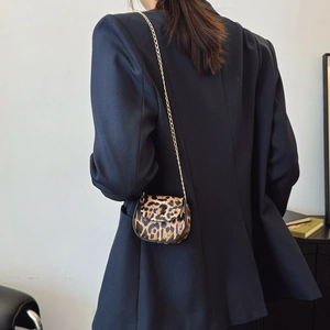 Mini leopard print saddle bag with gold chain strap worn by model over a dark blazer