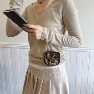 Mini leopard print crossbody saddle bag with gold chain strap shown on model