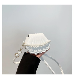 Détail du mini sac blanc en forme de coquille avec anse en perles et boucles dorées