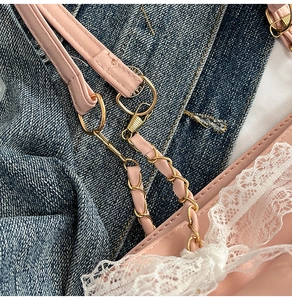 Détail macro du cuir rose avec bordure en dentelle blanche et boucle de chaîne dorée