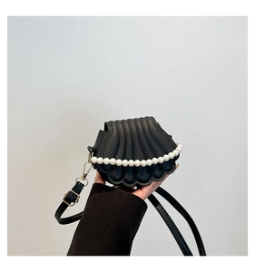 Détail du sac coquille noir mat avec bordure en perles et finitions dorées