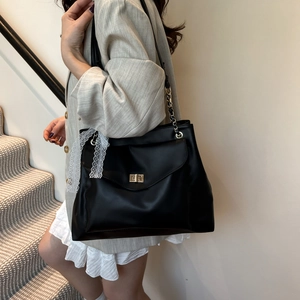 Sac fourre-tout vintage noir avec boucle dorée et nœud en dentelle, porté par mannequin