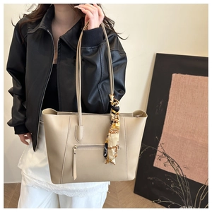 Detail of beige leather tote bag with stylish patterned silk scarf on the handle