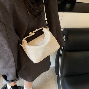 Sac bandoulière tissé crème chic avec finitions dorées porté par un mannequin