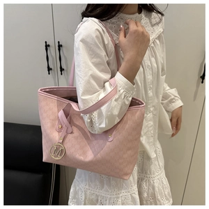 Detailed side view of a pink monogram tote bag showing metal logo charm and large capacity