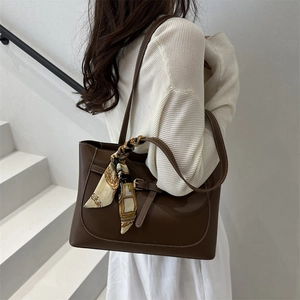 Grand sac cabas en cuir marron avec détail foulard en soie porté par un mannequin chic