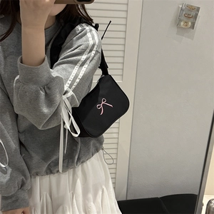 French design black shoulder bag with pink bow detail shown in a mirror selfie