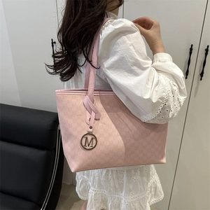 Pink large tote bag with M letter pattern and gold logo charm shown on a model