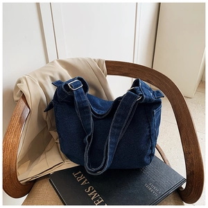 Close-up of dark blue denim crossbody bag with adjustable strap and silver metal buckle