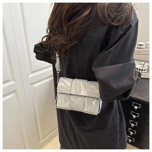 Detail of silver woven crossbody bag with metallic texture and adjustable strap
