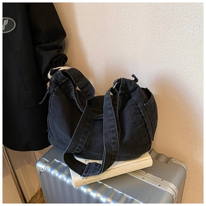 Detail shot of large capacity black washed denim hobo shoulder bag on a suitcase