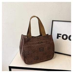 Détail du sac cabas en velours côtelé marron avec motifs ours et poches frontales