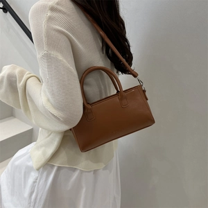 Brown matte leather tote bag with double handles and fashion engraving in a side view display