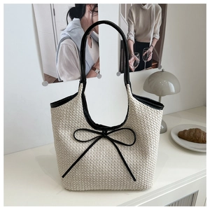 Close-up of woven tote bag featuring creamy V-shape texture and black leather bow detail