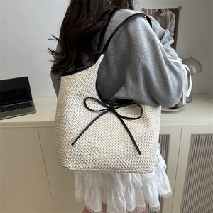 Fashionable woven straw shoulder bag with black bow detail and slim straps