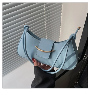 Close-up of light blue crescent leather shoulder bag with gold metallic buckle and knot detail