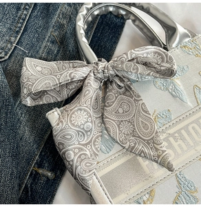 Macro shot of butterfly embroidery detail and silver textured handle on the handbag