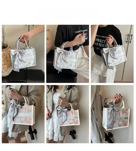 Detail of embroidered tote bag with fashion letter band and stylish silk scarf on handle
