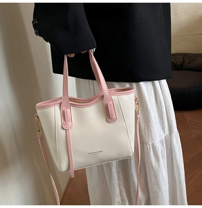 Detail of fashion tote bag featuring cream base with pink trim and long shoulder strap