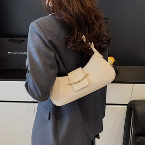 Minimalist cream white half-moon shoulder bag with elegant gold metal trim on model