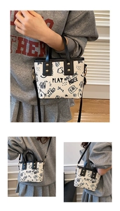 Detail of white graffiti tote bag featuring black print, gold rivets and detachable strap