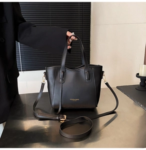 Close-up of black leather bucket bag with gold lettering and adjustable shoulder strap