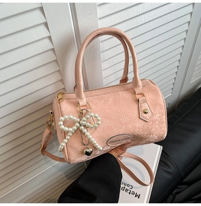 Detail view of pink snake-pattern Boston bag with pearl bow and metal heart charm