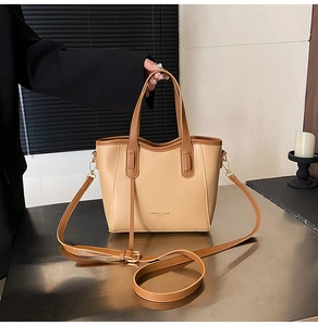 Close-up of dual-tone leather bucket bag with gold lettering and adjustable strap