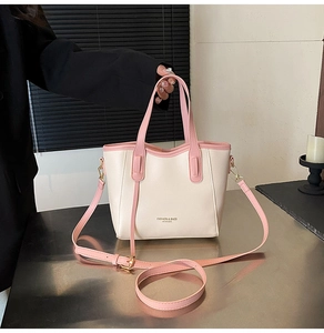 Detailed shot of trendy PU leather bucket bag with contrasting pink handles and adjustable strap