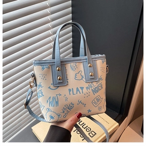 Close-up of light blue and beige tote bag with cute graffiti prints and golden rivets