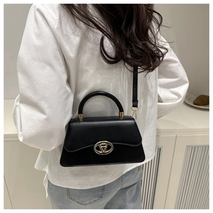 Chic black matte leather crossbody bag with gold metal logo hardware worn on shoulder