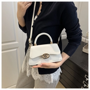 Close-up of minimalist white leather shoulder bag with a gold oval geometric metal clasp